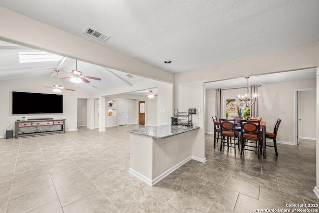 kitchen featuring baseboards, visible vents, dark stone counters, open floor plan, and vaulted ceiling with beams