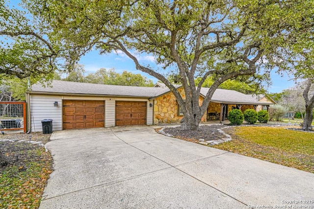 view of front facade with an attached garage, stone siding, and concrete driveway