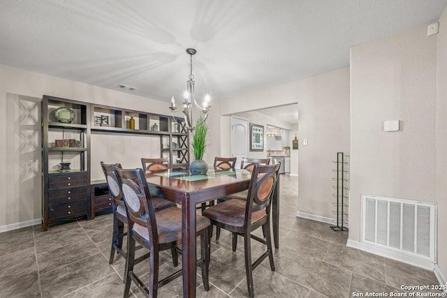 dining space featuring a chandelier, visible vents, and baseboards