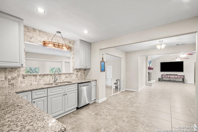 kitchen featuring backsplash, decorative light fixtures, light stone countertops, stainless steel dishwasher, and a sink