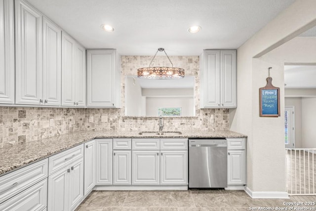 kitchen featuring light stone counters, a sink, white cabinetry, hanging light fixtures, and stainless steel dishwasher