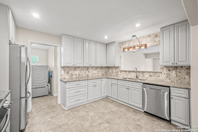 kitchen with appliances with stainless steel finishes, white cabinets, decorative light fixtures, and a sink