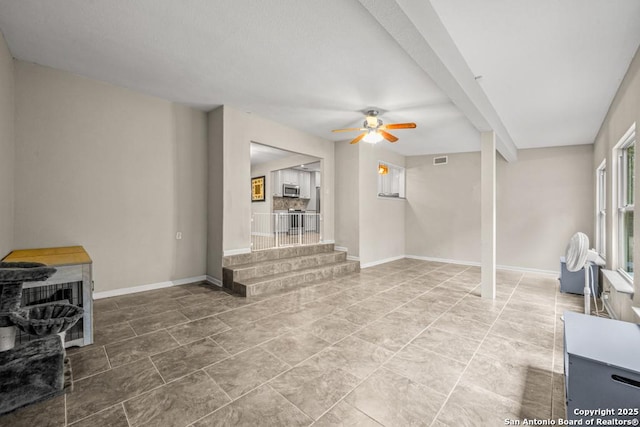 interior space with baseboards, visible vents, and a ceiling fan