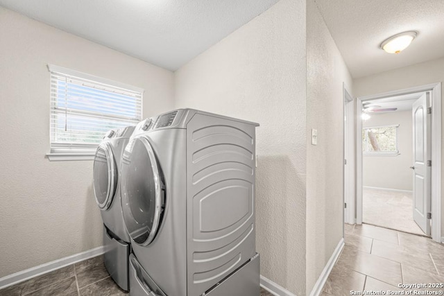 washroom featuring a textured ceiling, a textured wall, laundry area, baseboards, and independent washer and dryer