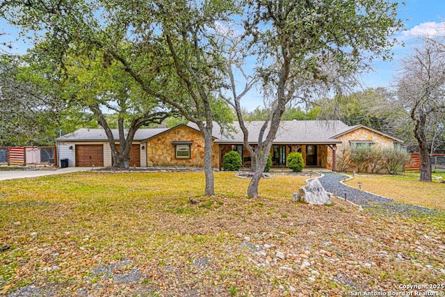 single story home with a garage, stone siding, a front lawn, and driveway