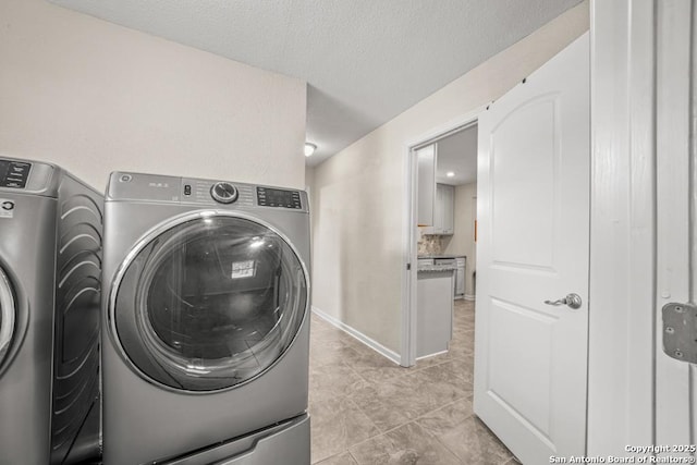 laundry area with washer and dryer, laundry area, and a textured ceiling