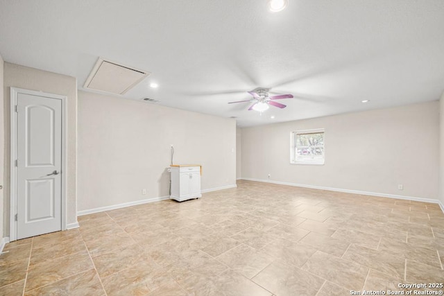 unfurnished room featuring baseboards, visible vents, a ceiling fan, and attic access