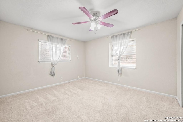 empty room with a ceiling fan, light colored carpet, and baseboards