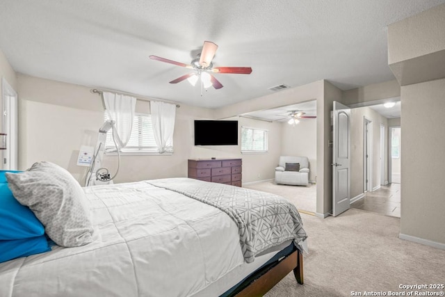 bedroom with light colored carpet, visible vents, baseboards, and multiple windows