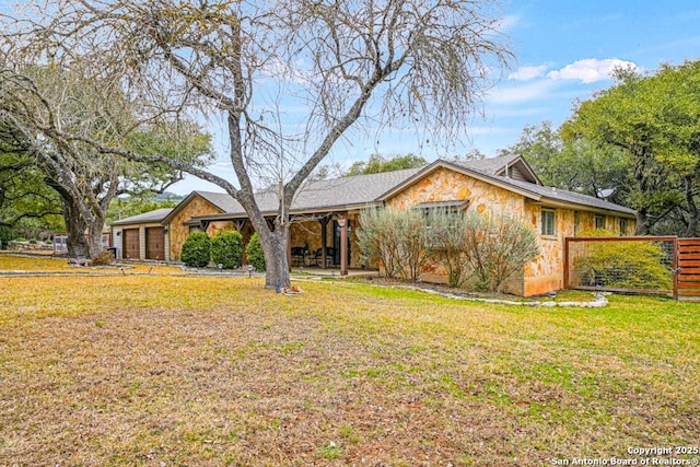 view of front of property featuring stone siding, fence, and a front yard