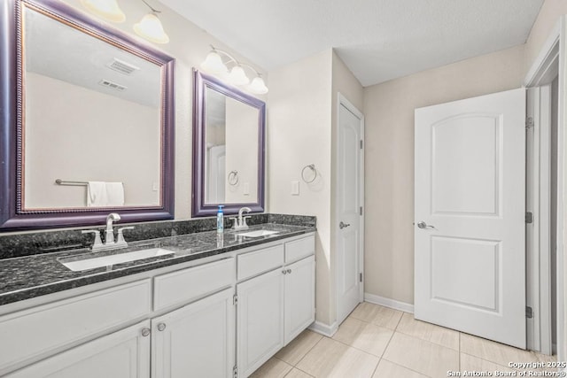 bathroom with double vanity, visible vents, a sink, and tile patterned floors