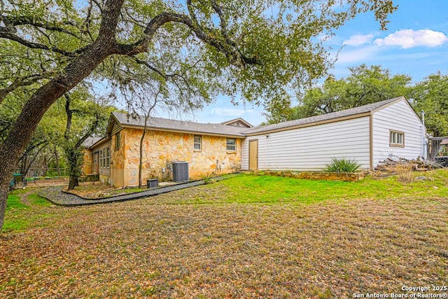 back of property featuring stone siding, a yard, and central AC unit