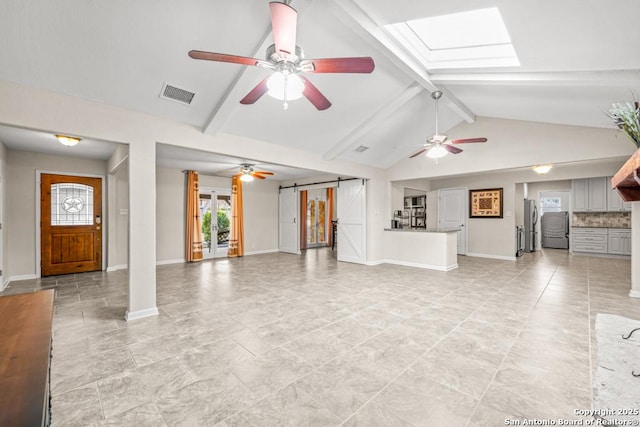 unfurnished living room with vaulted ceiling with skylight, visible vents, baseboards, and a barn door