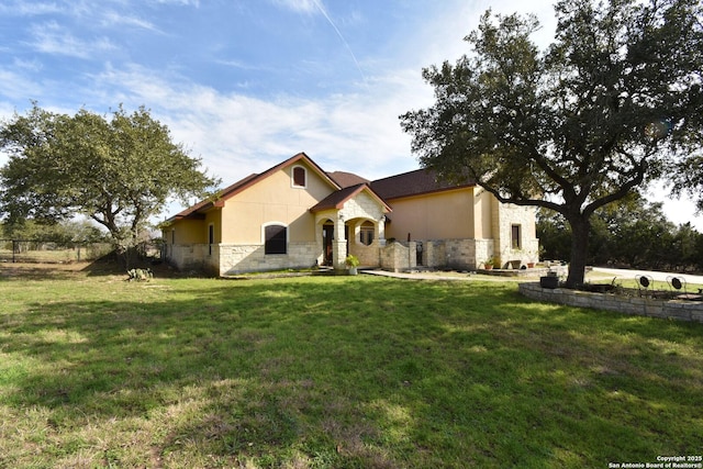 view of front facade with stone siding, a front lawn, and stucco siding