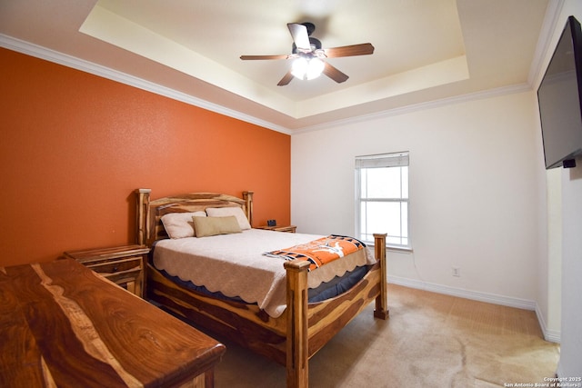 bedroom with carpet floors, a ceiling fan, baseboards, ornamental molding, and a tray ceiling