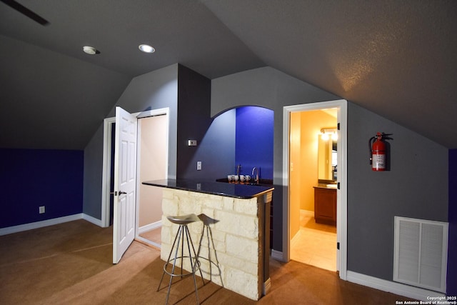 bar with indoor wet bar, carpet, visible vents, and baseboards