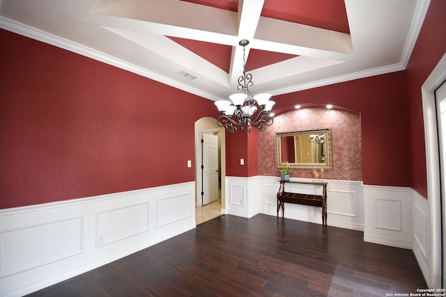 unfurnished dining area featuring arched walkways, a wainscoted wall, dark wood-style floors, a tray ceiling, and a chandelier