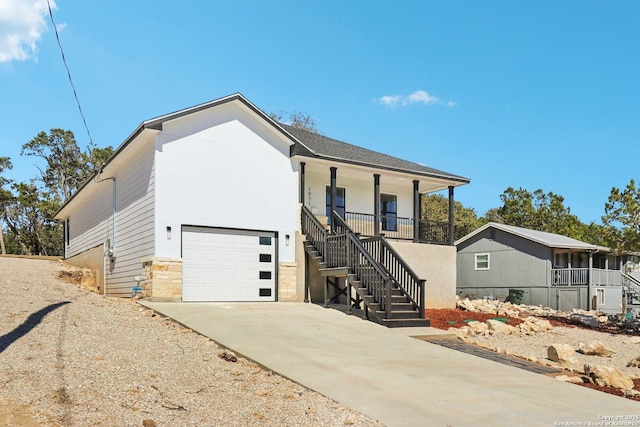 view of front facade with a porch, concrete driveway, an attached garage, stone siding, and stairs