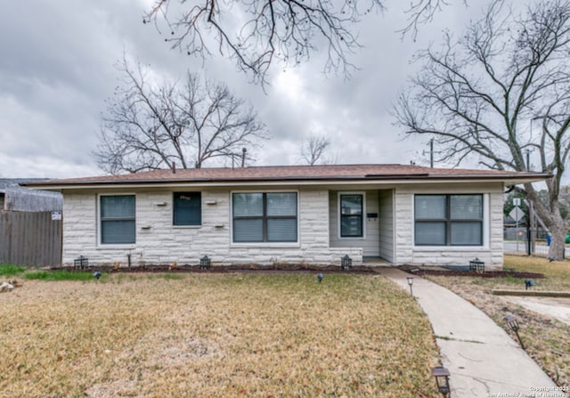 ranch-style house with stone siding, fence, and a front lawn