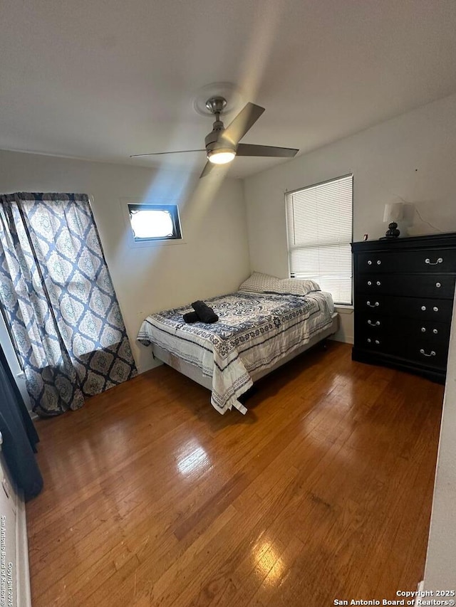 bedroom with multiple windows, a ceiling fan, and dark wood-type flooring