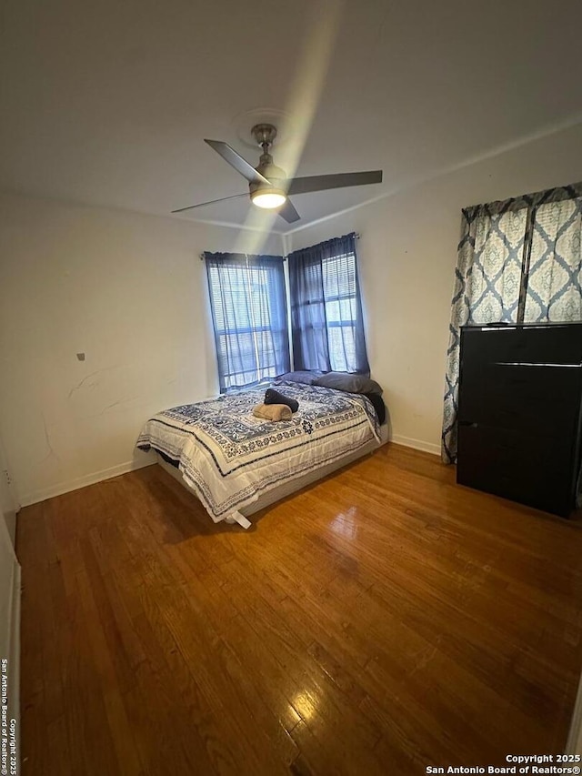 unfurnished bedroom featuring a ceiling fan, baseboards, and wood finished floors