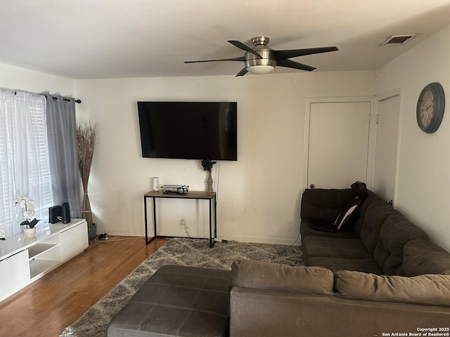 living area featuring baseboards, dark wood-style flooring, visible vents, and a ceiling fan