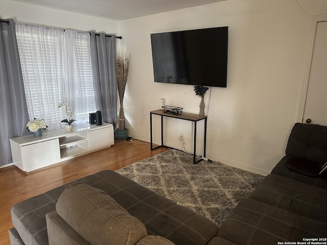 living room with a healthy amount of sunlight, baseboards, and wood finished floors