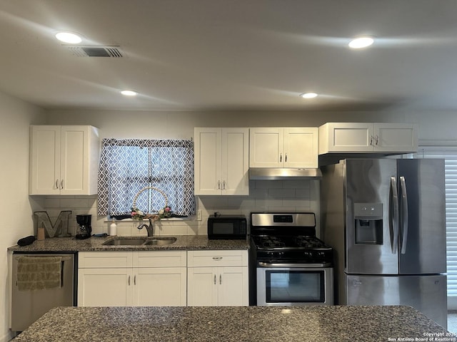 kitchen with appliances with stainless steel finishes, white cabinets, a sink, and under cabinet range hood