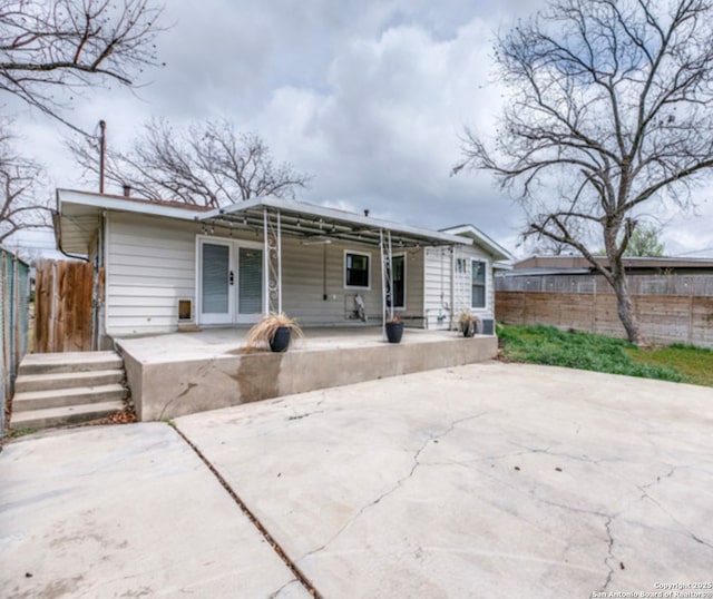 rear view of property with french doors, a patio area, and fence