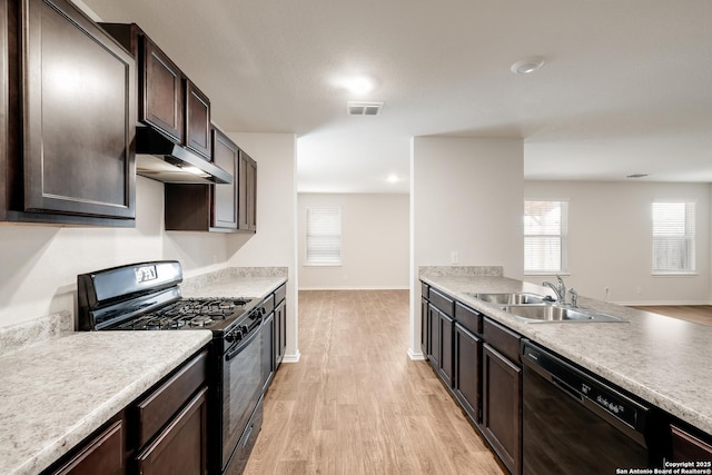 kitchen with visible vents, light countertops, a sink, under cabinet range hood, and black appliances