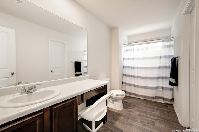 full bath with visible vents, a shower with shower curtain, toilet, wood finished floors, and vanity