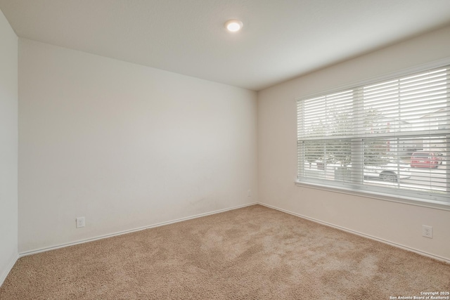 spare room with light carpet and baseboards