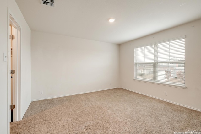 empty room featuring light carpet, visible vents, and baseboards