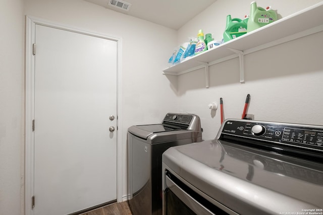 clothes washing area with laundry area, washing machine and dryer, visible vents, and dark wood-style flooring