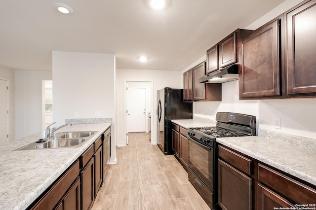 kitchen with light countertops, a sink, dark brown cabinets, under cabinet range hood, and black appliances