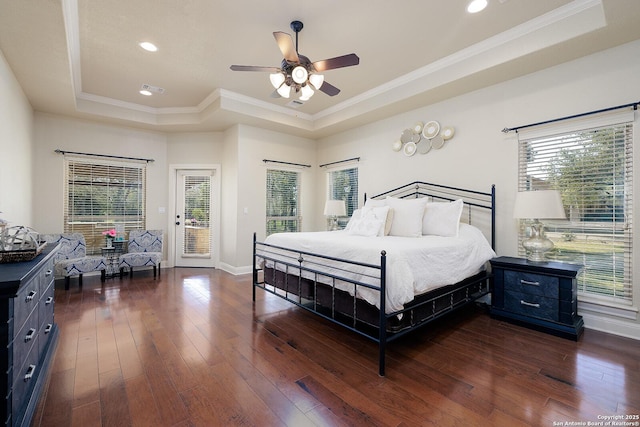 bedroom with dark wood-style floors, crown molding, a tray ceiling, and access to exterior