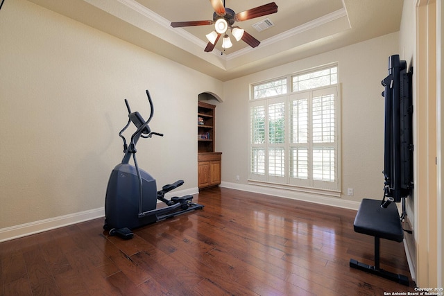 exercise room with visible vents, ornamental molding, hardwood / wood-style flooring, baseboards, and a raised ceiling