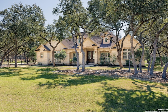 french country style house with a front yard and stone siding