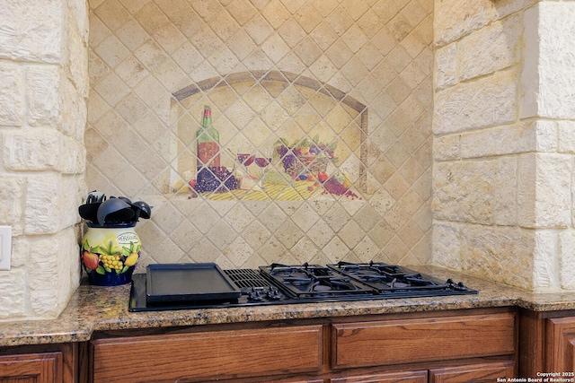 kitchen featuring decorative backsplash, brown cabinets, stone countertops, and black gas stovetop