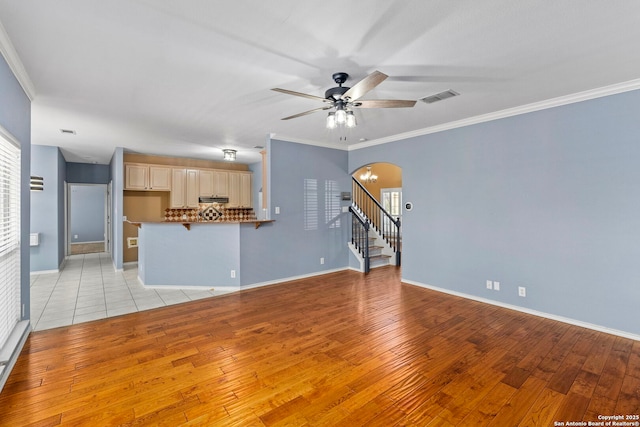 unfurnished living room featuring visible vents, stairs, arched walkways, and ornamental molding