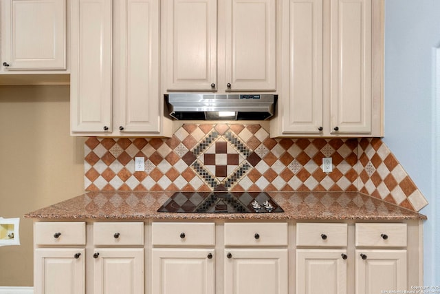 kitchen with white cabinets, light stone counters, black electric cooktop, and under cabinet range hood