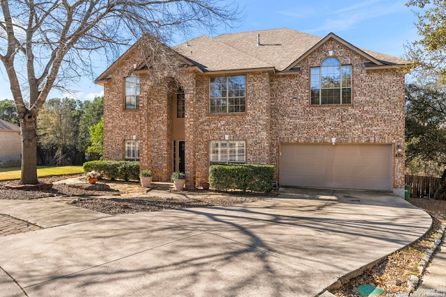 traditional-style home with a garage, brick siding, driveway, and roof with shingles