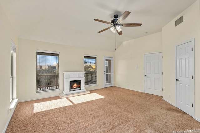 unfurnished living room with visible vents, a ceiling fan, a glass covered fireplace, lofted ceiling, and light colored carpet