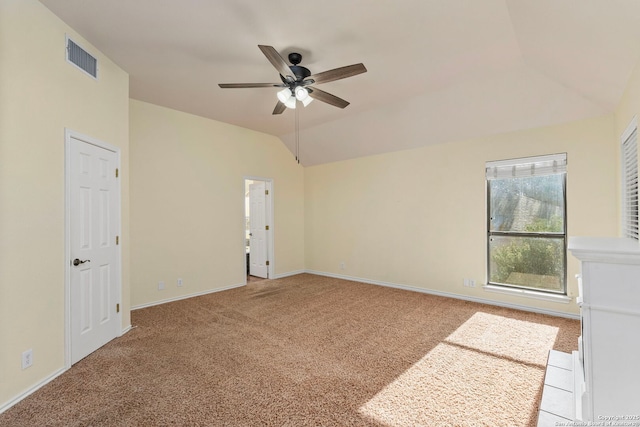 spare room featuring a ceiling fan, lofted ceiling, light colored carpet, and visible vents