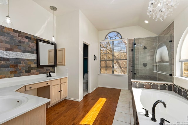 full bathroom featuring a stall shower, lofted ceiling, toilet, a garden tub, and vanity