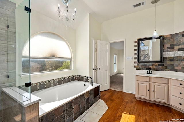 full bathroom with visible vents, backsplash, vanity, wood finished floors, and a bath