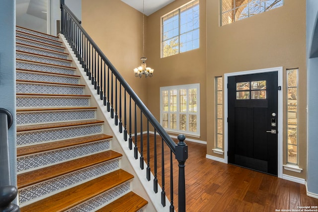 foyer with dark wood-style floors, stairway, baseboards, and a notable chandelier