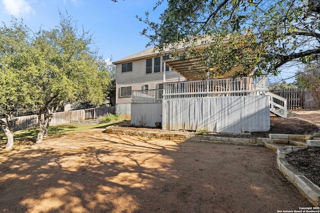 back of house featuring fence, a wooden deck, and stairs