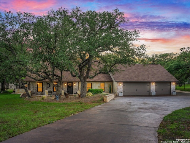 view of front of house with concrete driveway, a lawn, and an attached garage