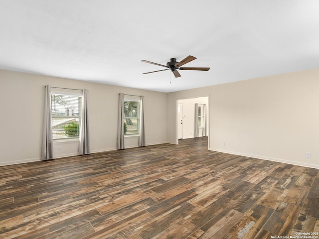 spare room with dark wood-style flooring, a ceiling fan, and baseboards